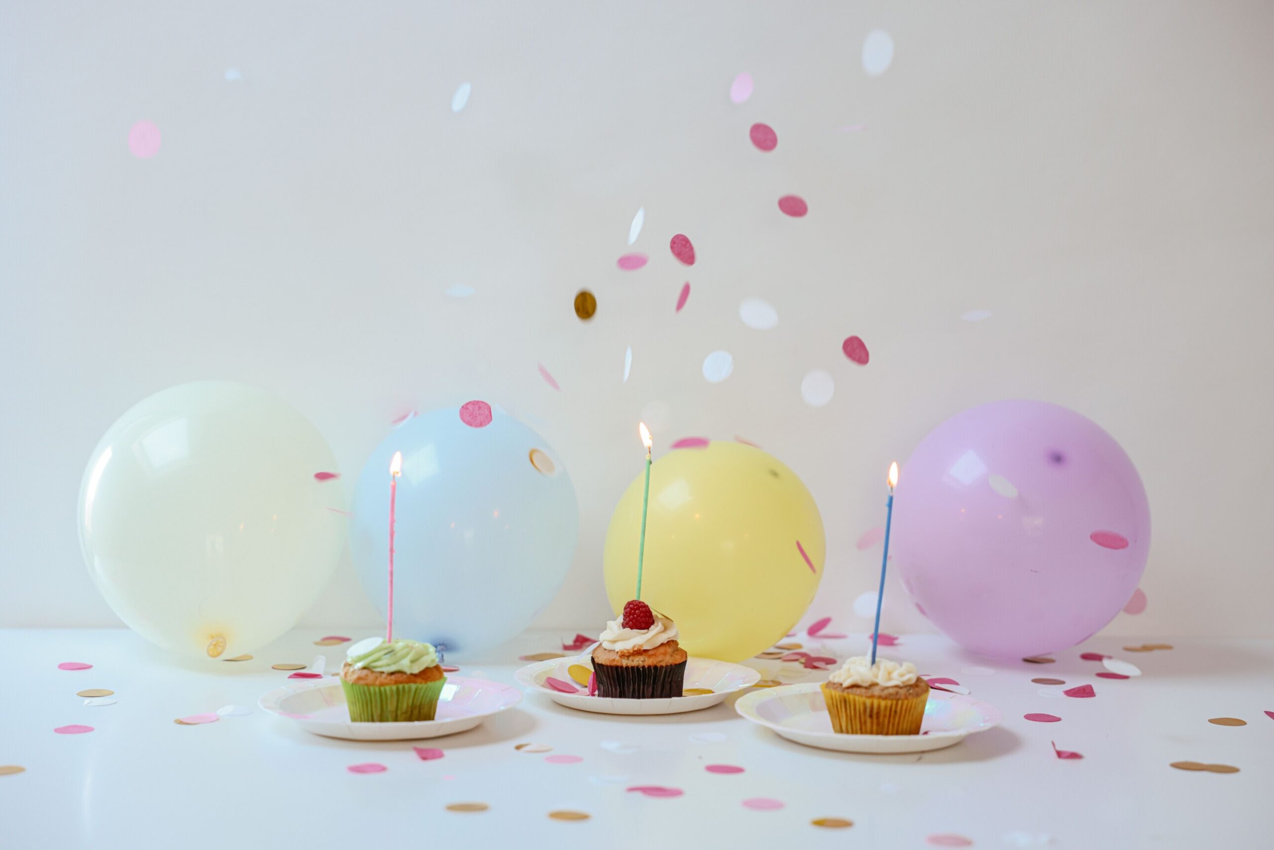 Vibrant birthday setup with cupcakes, balloons, and confetti on a table.